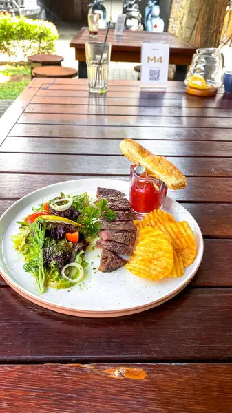 Tahta bir masada çatallı lezzetli bir bifteğin yüksek açılı görüntüsü.