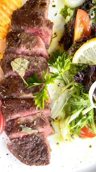 Sebzeli biftek ve beyaz tabakta sos.