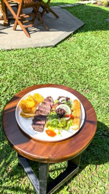 Bahçe masasında biftek ve ızgara biftek.