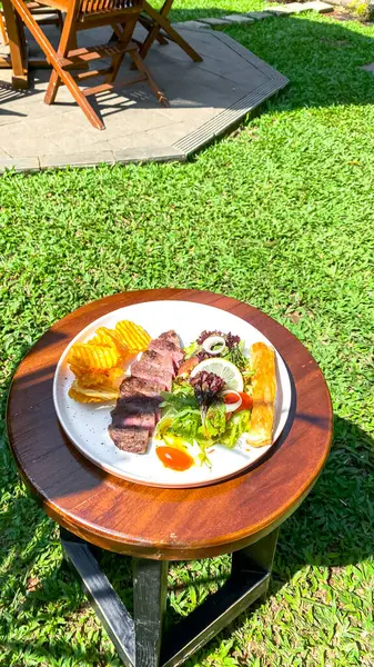 Bahçe masasında biftek ve ızgara biftek.