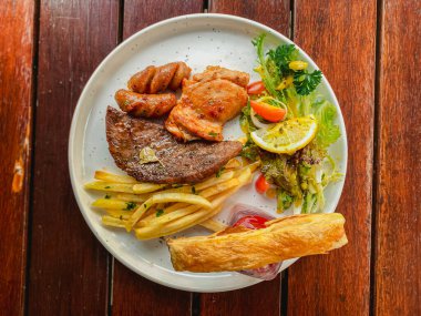 Kızarmış patates ve salata masada beyaz bir tabakta servis edilir.