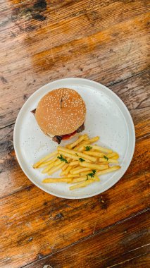 Tahta yüzeyde patates kızartması ve yüksek açılı bir hamburger.