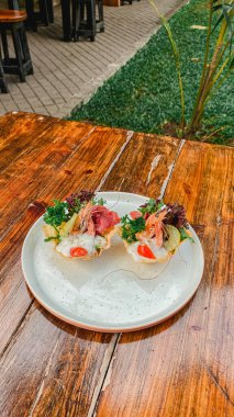 Tahta masada taze sebzeli, peynirli ve balıklı bir tabak..