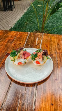 Tahta bir masada sebzeli ve etli bir tabak lezzetli sandviç.