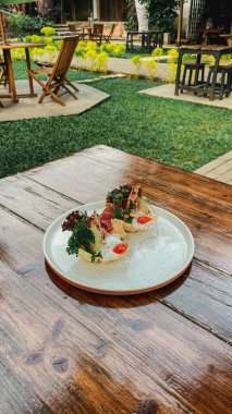 Bir tabak et, peynir ve sebze parktaki ahşap masada.