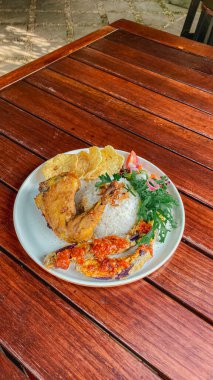 Ahşap bir masada ızgara tavuk ve sebze.