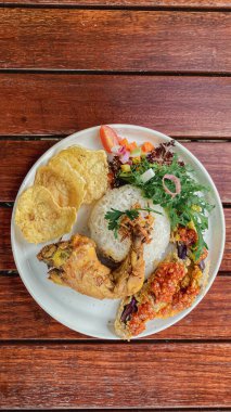 Kızarmış tavuk, pilav, sebze ve salata, kızarmış tavukla servis edilir.