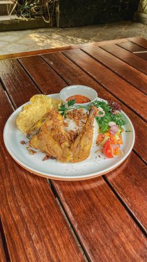 Ahşap bir masada sebzeli ızgara tavuk ve sos.