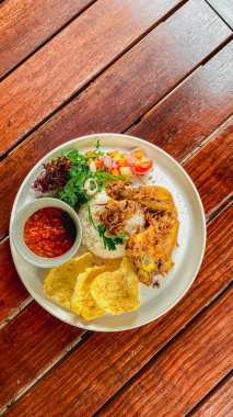 Ahşap masada soslu kızarmış tavuk ve sebze salatası.