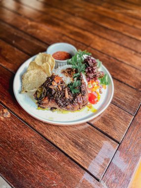 Ahşap arka planda salata, sebze ve baharatlı ızgara biftek.