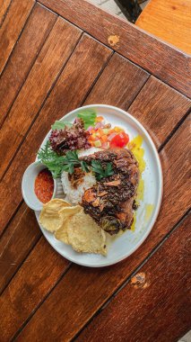 Sebzeli ızgara tavuk bifteği, tabakta kızarmış pirinç.