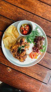 Ahşap bir masada sebzeli, lezzetli ve ızgara yemek.