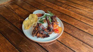 Tabakta tavuk kanadı, bir parça et, kızarmış patates ve sos.