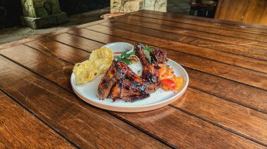 Tahta bir tabakta çatal ve sosla ızgara tavuk ve sebzelerden oluşan yüksek açılı bir çekim.