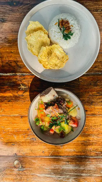 Kızarmış balık, pilav ve ahşap masada salata.