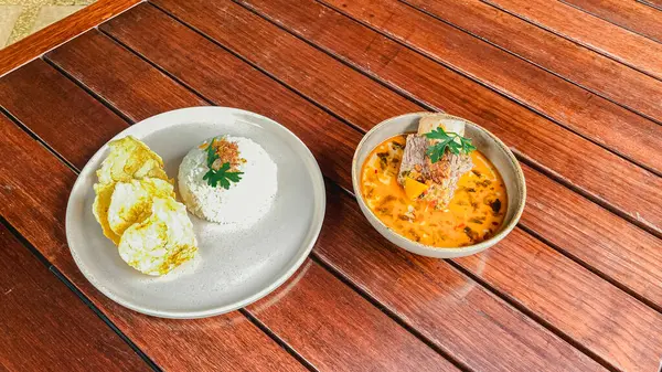 İki kase lezzetli kızarmış tavuk, baharatlı sos ve beyaz bir masada köri.