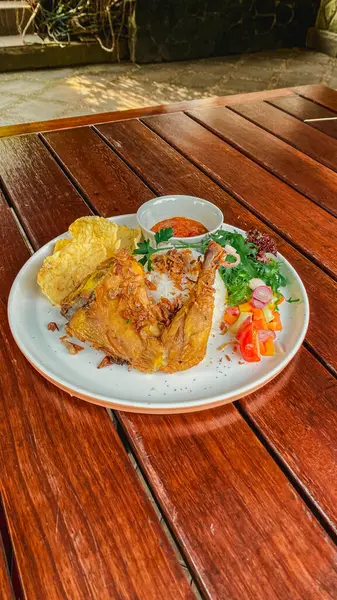 Ahşap bir masada sebzeli ızgara tavuk ve sos.