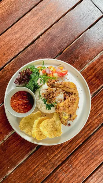 Ahşap masada soslu kızarmış tavuk ve sebze salatası.