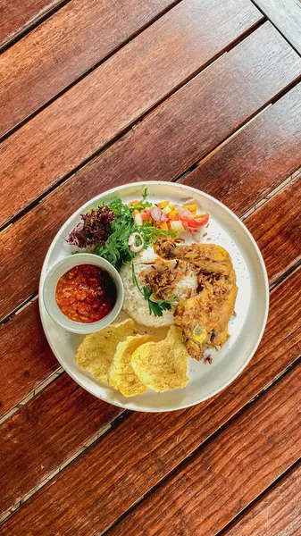 Endonezya yemeği: Kızarmış pirinç, kızarmış tavuk, kızarmış tavuk, ahşap arka planda beyaz bir tabakta yumurta ve sebze..
