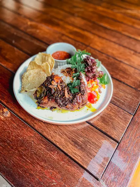 Ahşap arka planda salata, sebze ve baharatlı ızgara biftek.