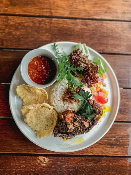Kızarmış tavuk, pirinç ve ahşap masada salata.