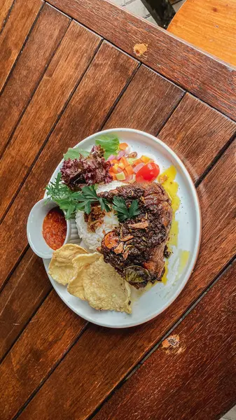 Sebzeli ızgara tavuk bifteği, tabakta kızarmış pirinç.