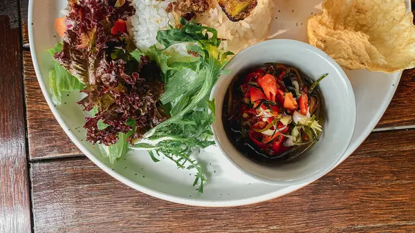 Ahşap bir arka planda tabakta kızarmış balık ve sebze..