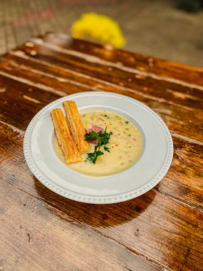 Tahta bir masada kremalı ve tavuklu beyaz bir tabağın yakın çekimi.