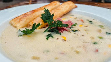 Sosisli çorba, ekmek ve sebzeler beyaz tabakta..