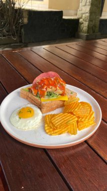 Tahta masada sandviç, peynir, domates, yumurta ve kahveyle kahvaltı..