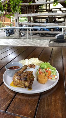 Tavuklu biftek, pirinç ve sebzeler ahşap masada.