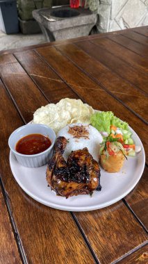 Ahşap bir masada ızgara domuz pirzolası, sebze ve sos.