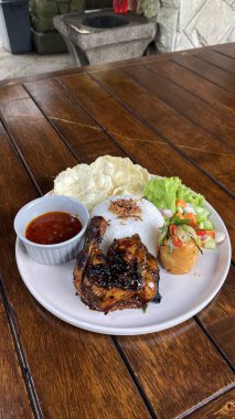 Ahşap arka planda sebzeli ızgara tavuk budu.