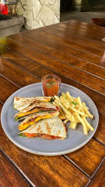 Lezzetli bir sandviçin dikey görüntüsü. Ahşap bir masada bolca et ve peynir.