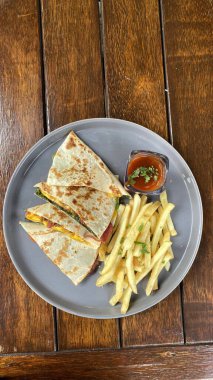 Lezzetli patates kızartması ve ahşap soslu bir tabağın yüksek açılı çekimi.