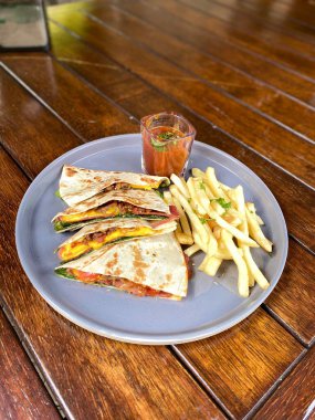 Bir tabak patates kızartması ve ahşap bir masada tavuk.