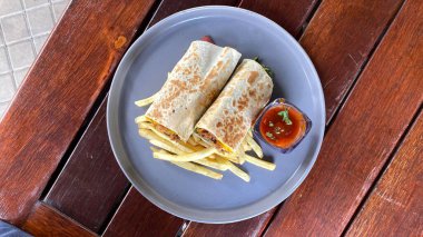 Etli sandviç, patates kızartması ve sos.