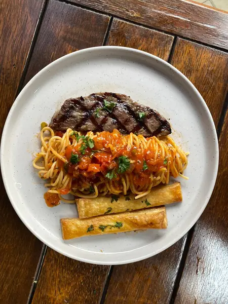 Izgara biftek ve domatesli spagetti.