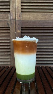 Bir fincan kahve ve bir bardak süt, ahşap arka planda.