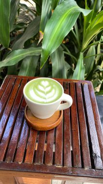 Kahve fincanı ve ahşap arka planda yeşil çay.