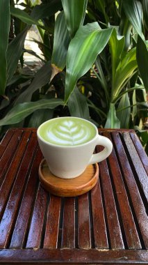 bir fincanda yeşil çay, bir fincan kahveyle ahşap bir masada