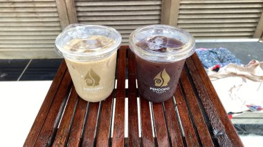 Kahve fincanı, çay ve kahve çekirdekleri ahşap masada.