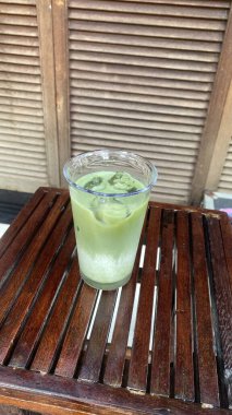 Bardakta taze meyve suyu ve ahşap zemin üzerinde buz küpleri.