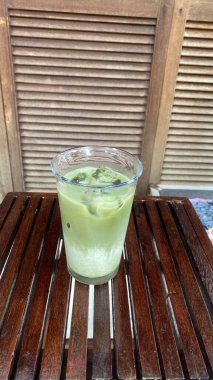 Tahta bir masada, bardakta yeşil çay.