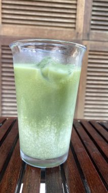 Bir bardak buzlu su ve ahşap masa üzerinde buz.