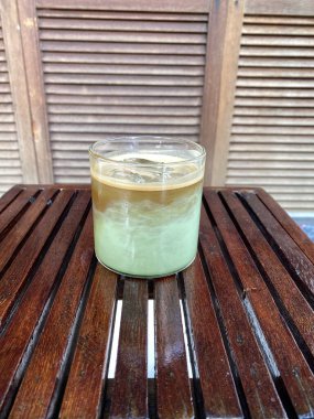 Tahta bir masada, cam bir fincanda yeşil çay