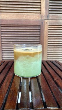 Tahta bir masada bir bardak süt ve cam kavanozda bir pipet.