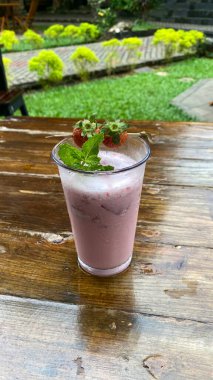 Tahta arka planda bir bardakta taze çilek.