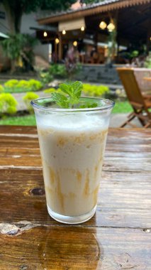 Bir fincan kahve, bir kaşık ve tahta bir masada kaşık.