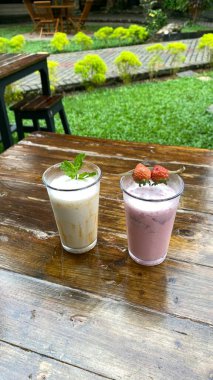 Bir fincan kahve, pipet ve bir bardak süt, ahşap bir masada..